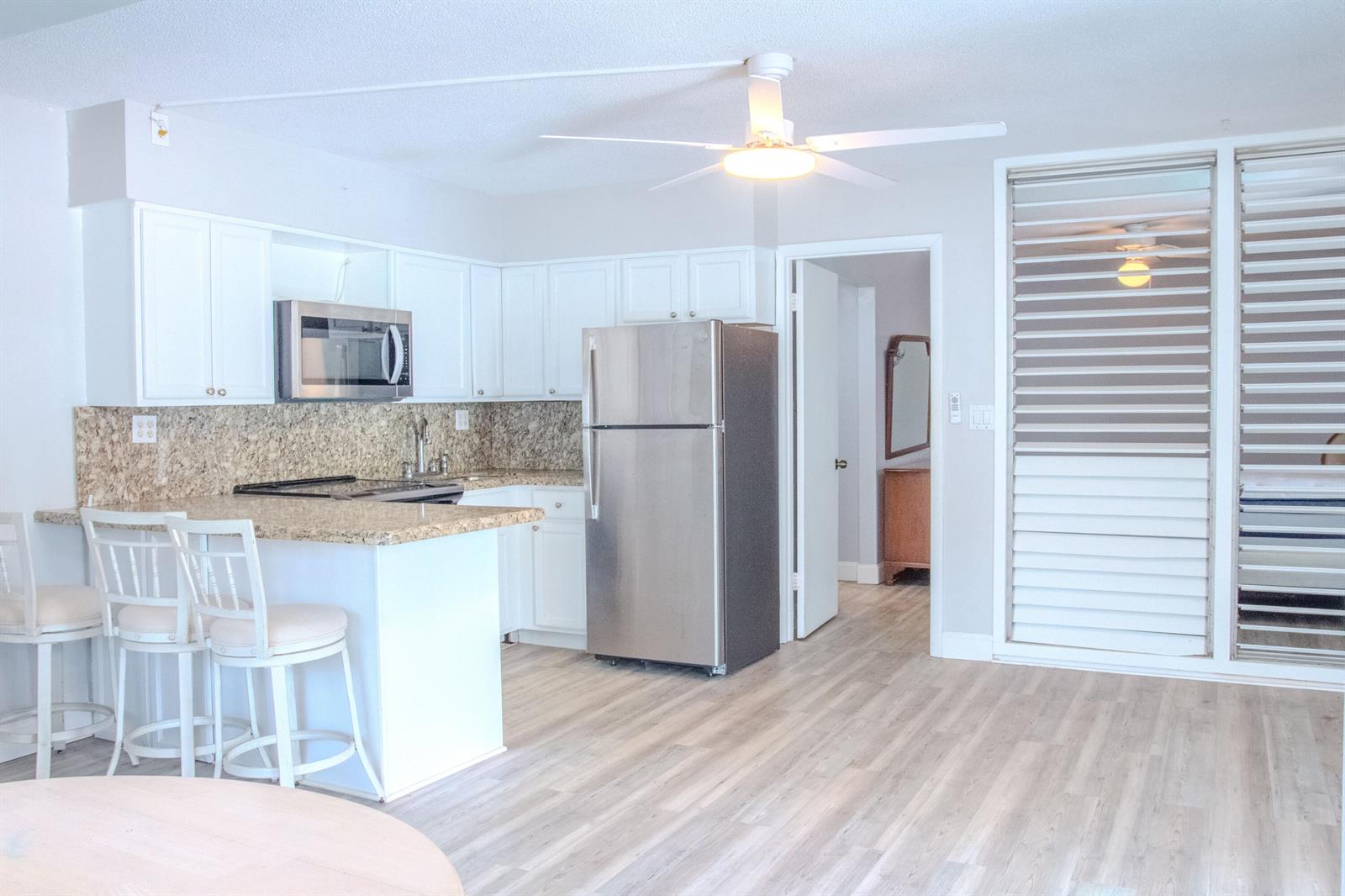 A kitchen with white cabinets, granite countertops, stainless steel appliances, and light wood flooring — 11000 S Ocean Drive # 12, Jensen Beach FL 34957, JENSEN BEACH, FL