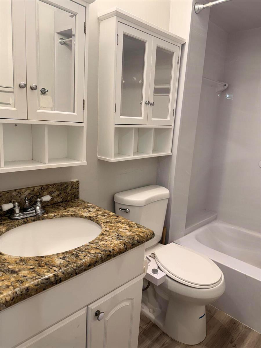A bathroom featuring a granite-topped vanity, white cabinets, a toilet with a bidet, and tub — 11000 S Ocean Drive # 12, Jensen Beach FL 34957, JENSEN BEACH, FL