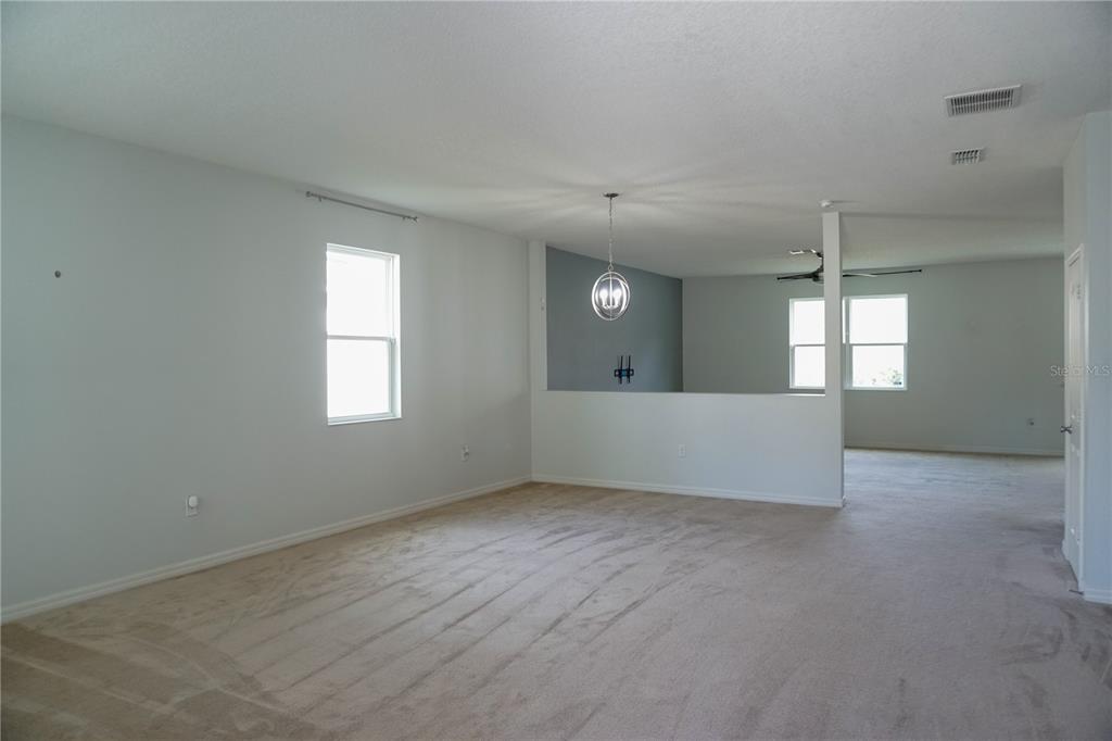 A carpeted room features a half-wall partition, a pendant light, and a blue accent wall — 2936 BOATING BOULEVARD, KISSIMMEE, FL