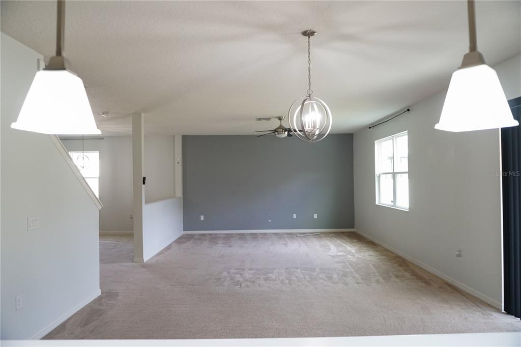 A living room features a gray accent wall, beige carpeting, and a modern globe chandelier — 2936 BOATING BOULEVARD, KISSIMMEE, FL