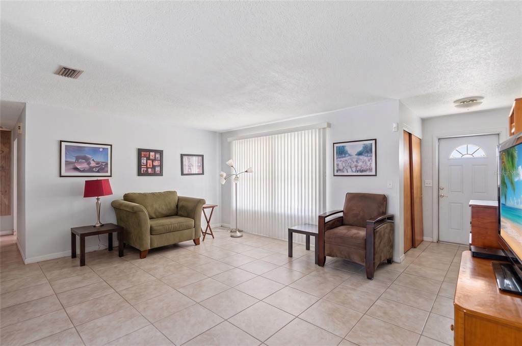 A living room with tile flooring, two armchairs, a television, and a large window — 915 MARTIN LUTHER KING BOULEVARD NE, WINTER HAVEN, FL