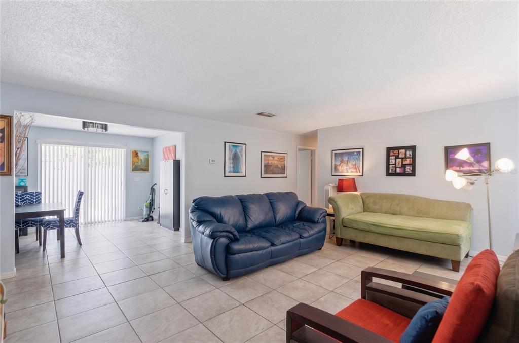 A living room with tile flooring, a blue sofa, a green sofa, and a dining area — 915 MARTIN LUTHER KING BOULEVARD NE, WINTER HAVEN, FL