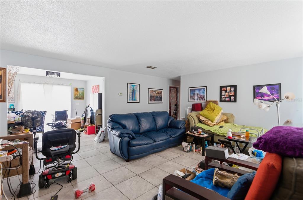 A living room with tile flooring, a blue sofa, and a mobility scooter — 915 MARTIN LUTHER KING BOULEVARD NE, WINTER HAVEN, FL
