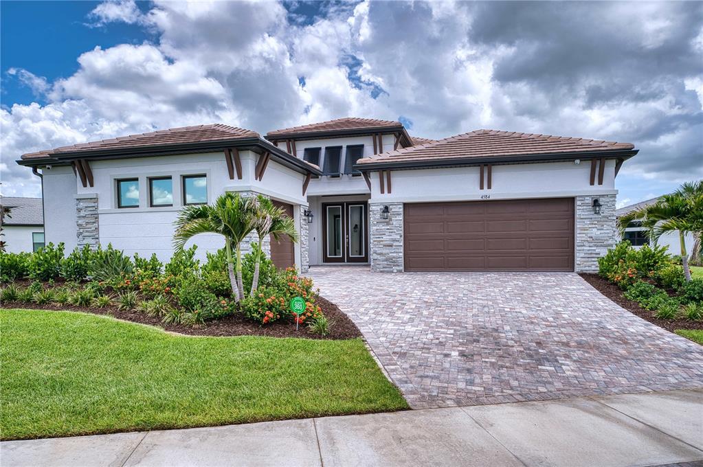 A single-story house with a tiled roof, stone accents, and a paved driveway — 4584 CEDRON COURT, SARASOTA, FL