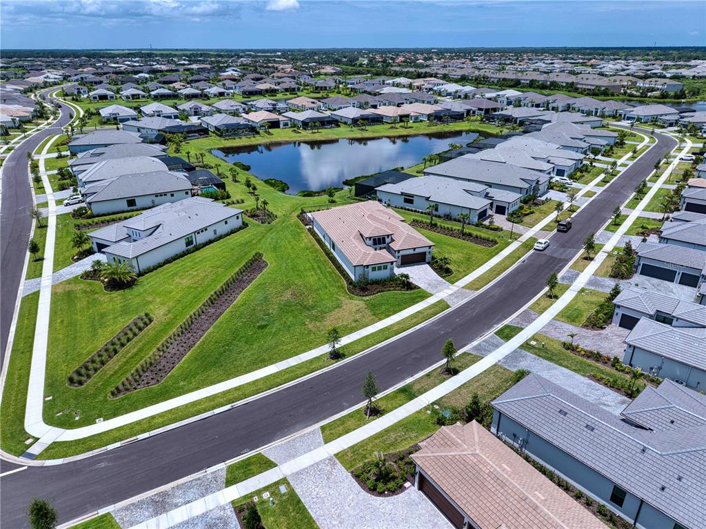 An aerial view shows a suburban neighborhood with houses surrounding a central pond — 4584 CEDRON COURT, SARASOTA, FL