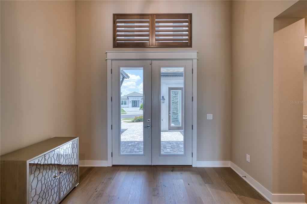 An entryway features double glass doors, a transom window, wood flooring, and a mirrored cabinet — 4584 CEDRON COURT, SARASOTA, FL
