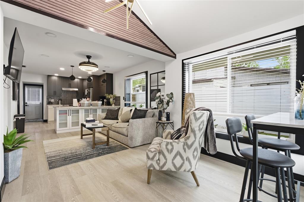 An open-concept living room and kitchen feature vaulted ceilings, light wood flooring, and modern decor — 2111 42ND STREET S, ST PETERSBURG, FL