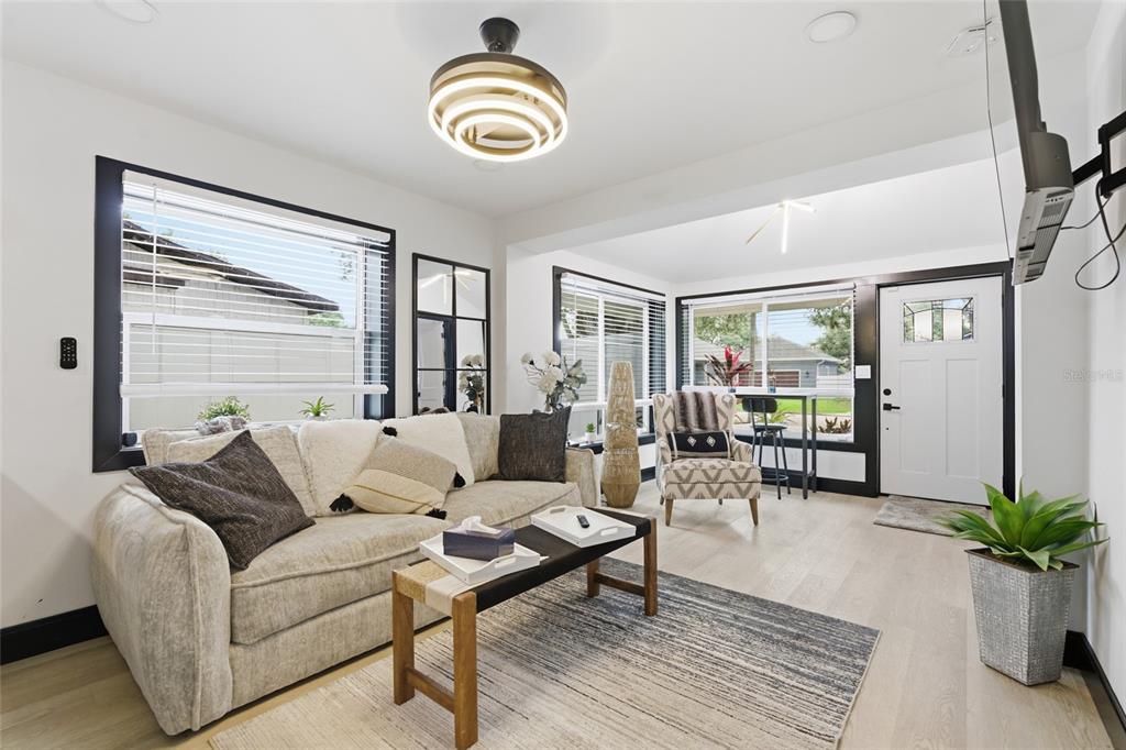 A living room features a light-colored sofa, a coffee table, and black-framed windows — 2111 42ND STREET S, ST PETERSBURG, FL