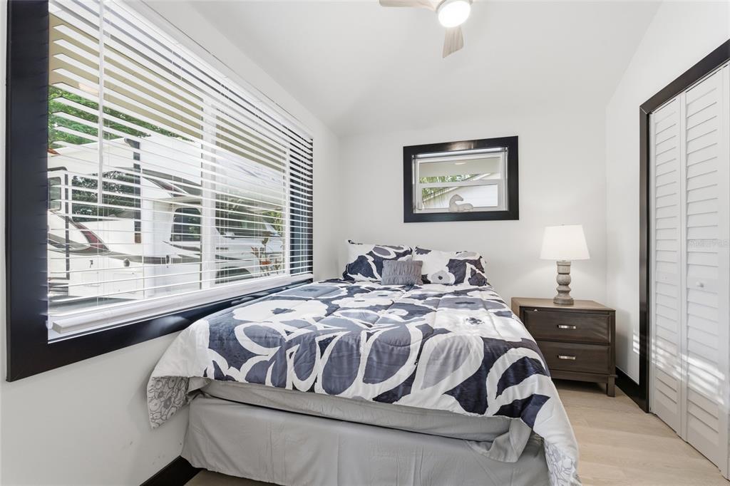 A bedroom features a bed with a floral comforter, a nightstand, and a large window — 2111 42ND STREET S, ST PETERSBURG, FL
