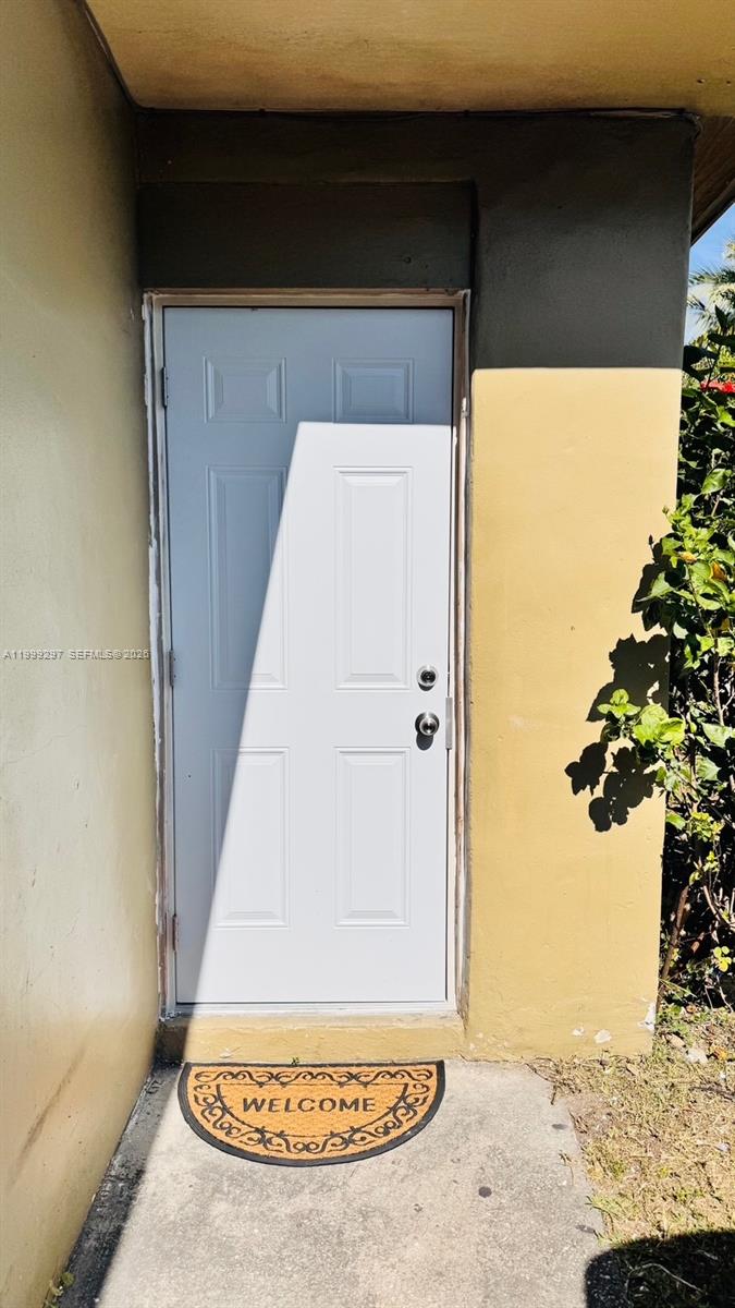 A white four-panel door with two locks is set into a tan exterior wall — 7530 NW 12th Ave side, Miami FL 33150, MIAMI, FL