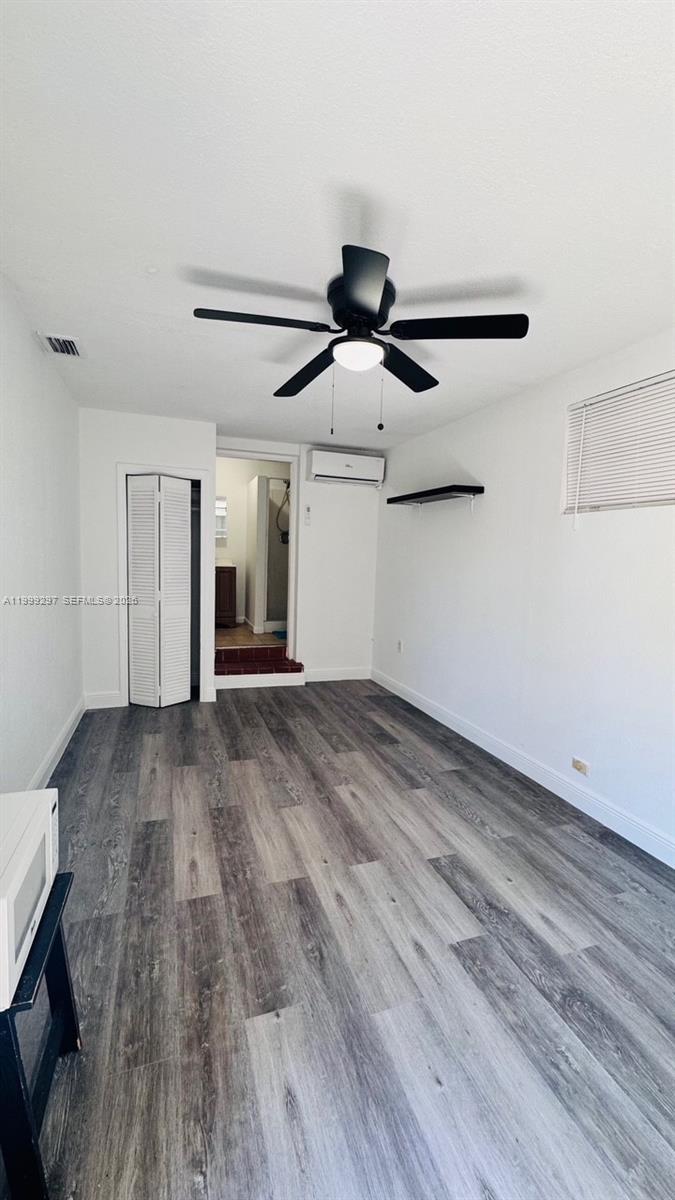 A room with gray wood-look flooring, a ceiling fan, a wall-mounted AC unit, and a closet — 7530 NW 12th Ave side, Miami FL 33150, MIAMI, FL