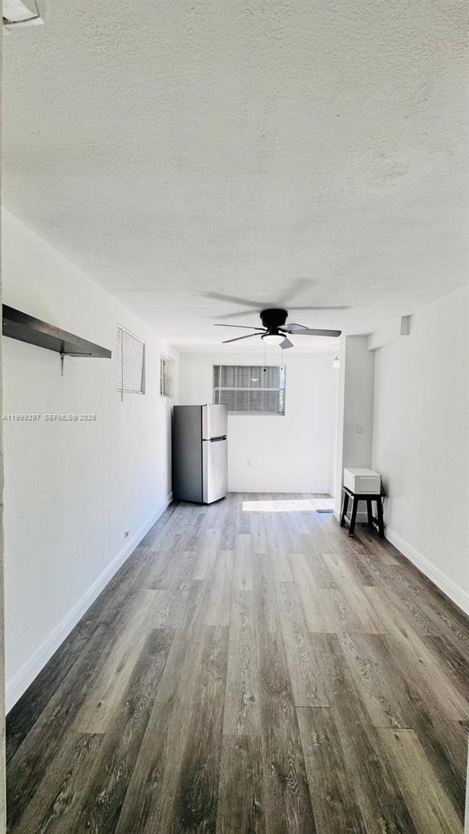 A narrow room features light wood-look flooring, white walls, a ceiling fan, and a refrigerator — 7530 NW 12th Ave side, Miami FL 33150, MIAMI, FL