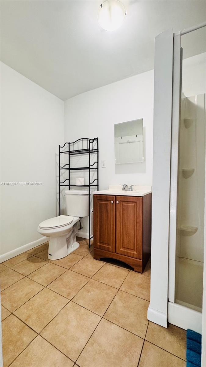 A bathroom features a toilet with a metal shelving unit, a wooden vanity, and a shower — 7530 NW 12th Ave side, Miami FL 33150, MIAMI, FL