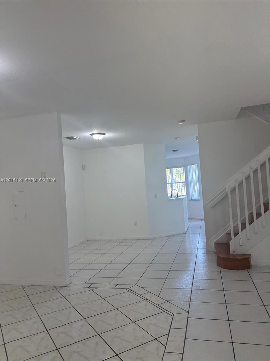 A room with white walls, tiled flooring, and a staircase with a wooden bottom step — 8525 SW 165th Pl # 8525, Miami FL 33193, MIAMI, FL