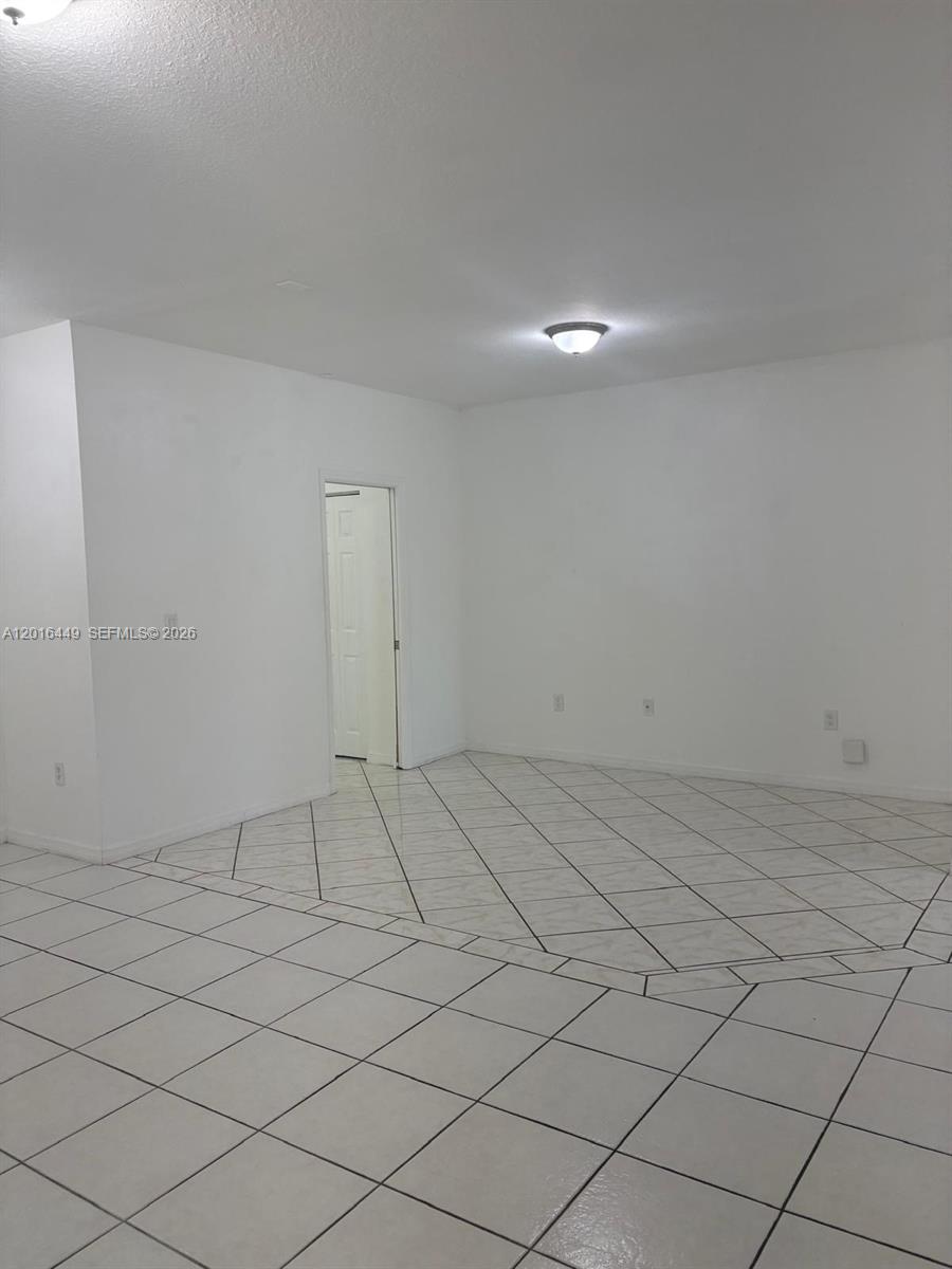 An empty room features white walls, a white tiled floor, and a doorway — 8525 SW 165th Pl # 8525, Miami FL 33193, MIAMI, FL