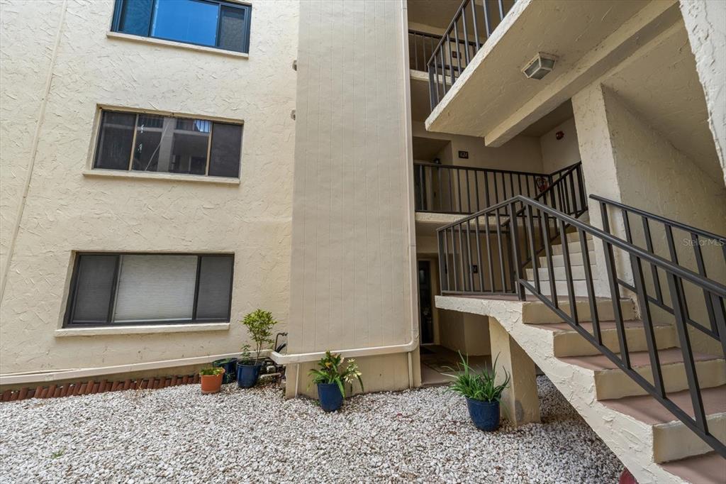 An exterior view of a multi-story apartment building with a staircase and gravel ground — 700 STARKEY ROAD UNIT 624, LARGO, FL