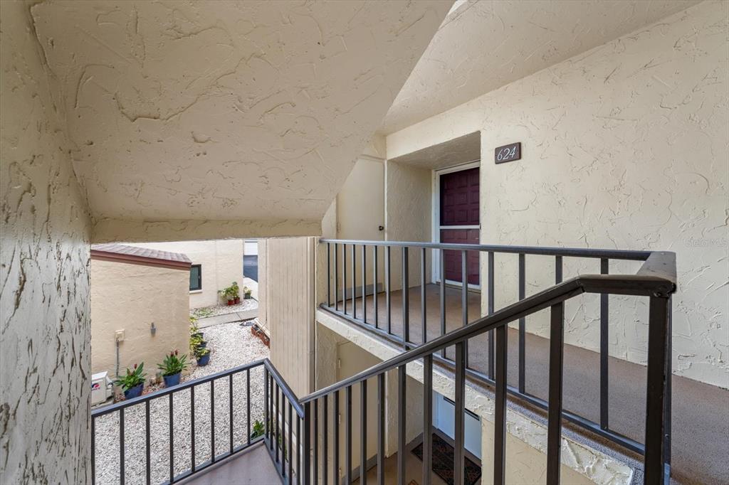 An exterior view of an apartment building staircase leading to a second-floor unit entrance — 700 STARKEY ROAD UNIT 624, LARGO, FL