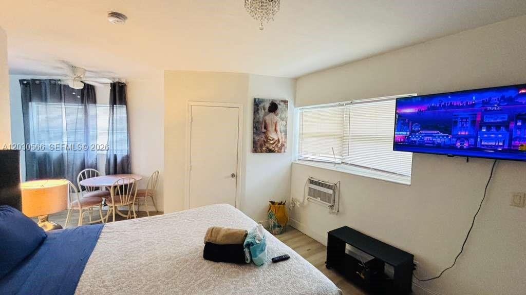 A bedroom features a bed, a dining table, a wall-mounted television, and a window unit — 109 SE 9th St # 2, Hallandale Beach FL 33009, HALLANDALE BEACH, FL