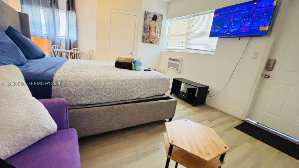 A bedroom features a bed, a purple armchair, a television, and a small wooden table — 109 SE 9th St # 2, Hallandale Beach FL 33009, HALLANDALE BEACH, FL