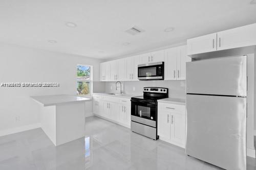 A modern kitchen features white cabinetry, stainless steel appliances, and a white kitchen island — 655 SW 5th St, Homestead FL 33030, HOMESTEAD, FL