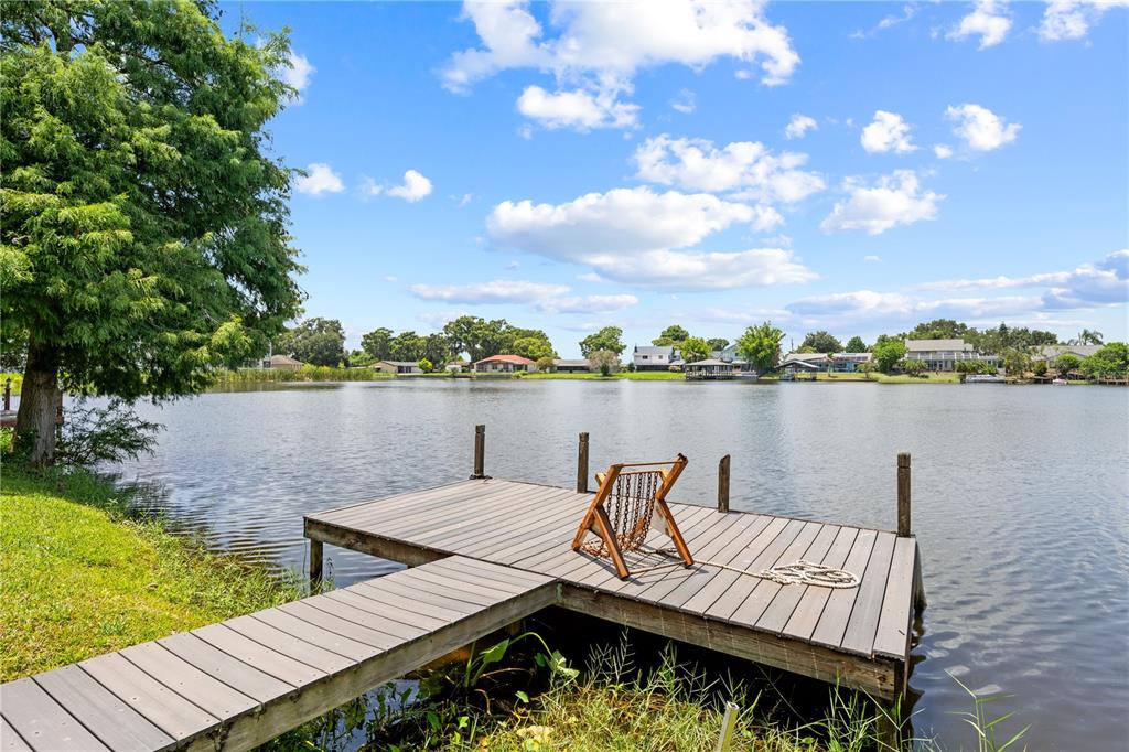 A wooden dock with a chair extends into a lake under a blue sky — 2705 EMERALD LAKE CT UNIT 2705, KISSIMMEE, FL