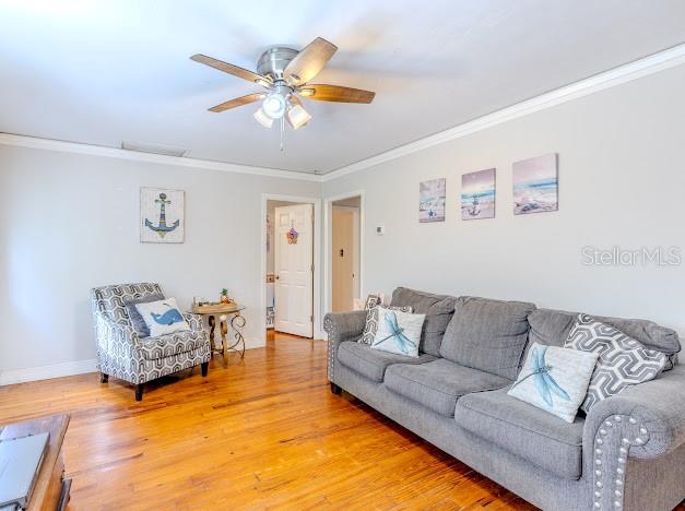 A living room features a grey sofa, an armchair, and a ceiling fan over wood floors — 11727 SW 122ND STREET, GAINESVILLE, FL