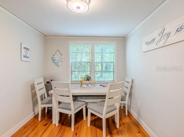 A dining area features a white table and chairs on hardwood floors under a ceiling light — 11727 SW 122ND STREET, GAINESVILLE, FL