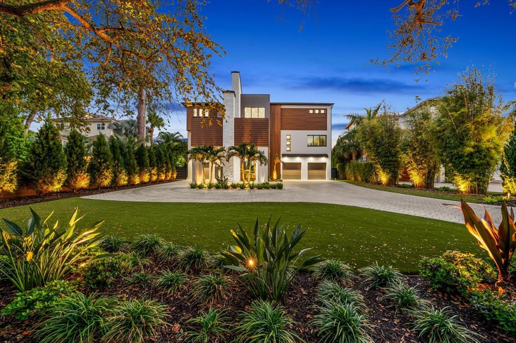 A modern two-story house with a stone chimney and paved driveway at dusk — 402 HILLSBOROUGH STREET, PALM HARBOR, FL