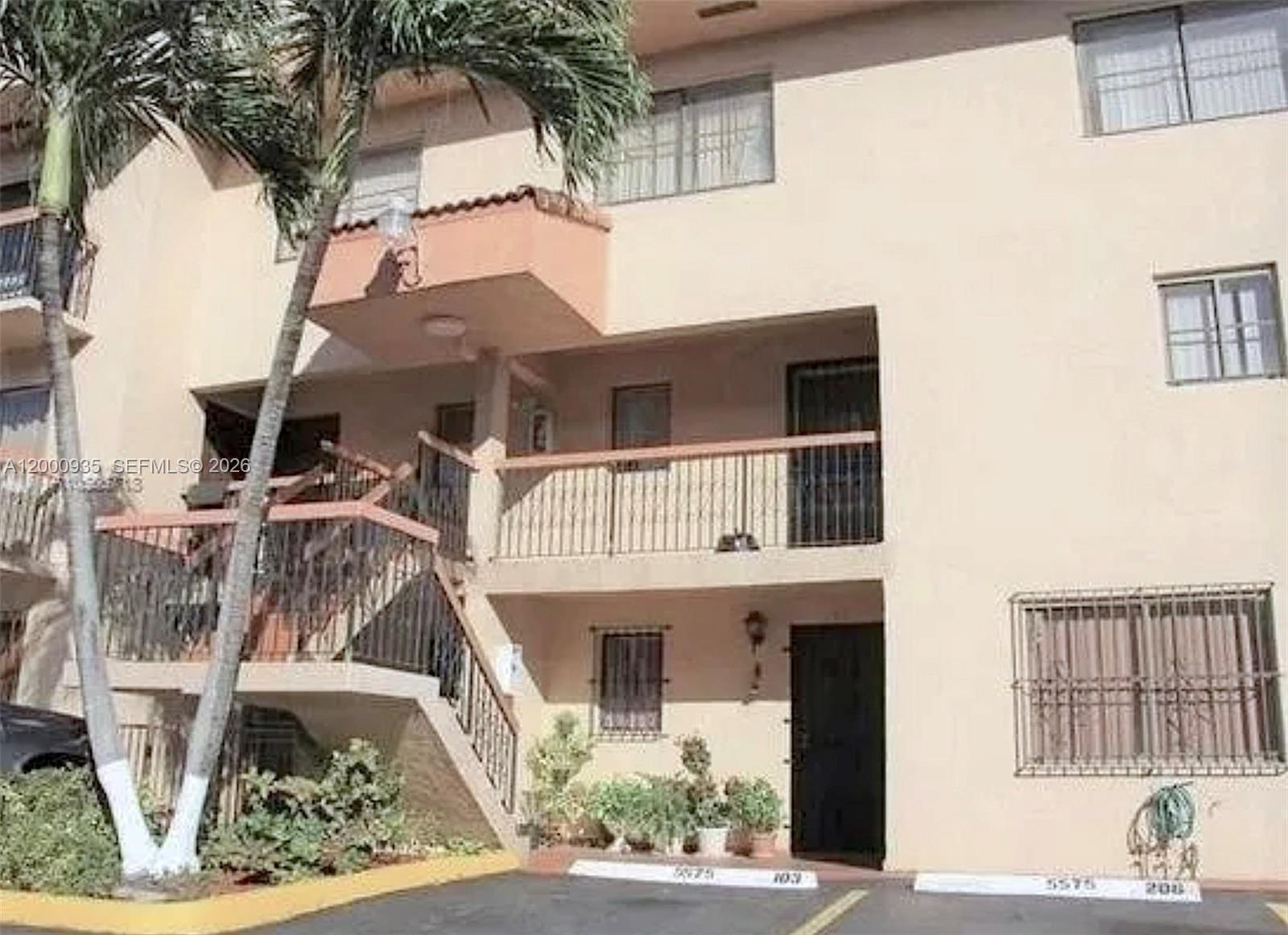 The exterior of a multi-story apartment building features a staircase, balconies, and parking spaces — 5575 W 26th Court # 203, Hialeah FL 33016, HIALEAH, FL