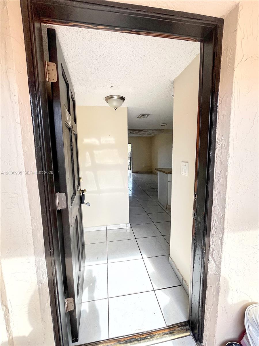 An open dark-framed door reveals an entryway with white tile floors leading into a room — 5575 W 26th Court # 203, Hialeah FL 33016, HIALEAH, FL