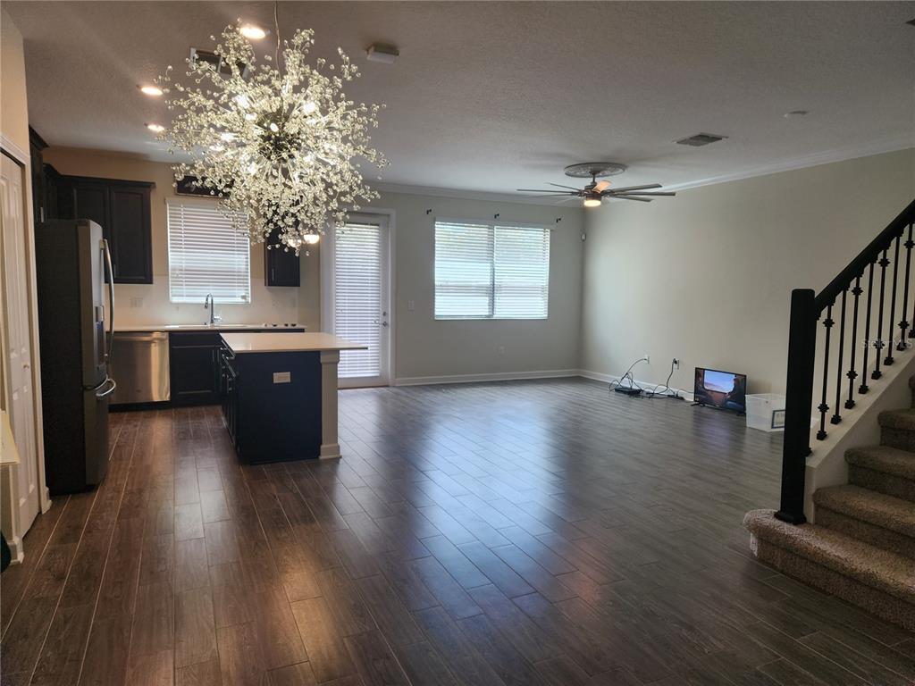 An open-concept kitchen and living area features dark wood cabinetry, tile flooring, and a chandelier — 8506 ARCADIA LANE, DAVENPORT, FL