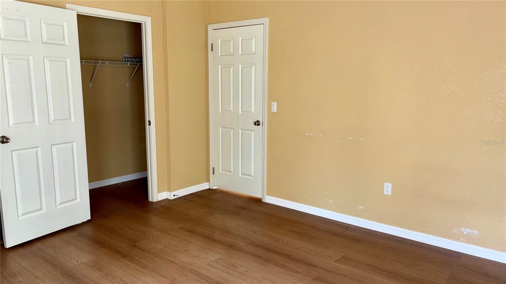 An interior room features light brown walls, wood-look flooring, a closet, and a closed door — 19112 IVERSON ROAD, LUTZ, FL