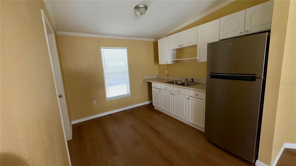 A kitchen features white cabinets, stainless steel appliances, and wood-look flooring — 19112 IVERSON ROAD, LUTZ, FL