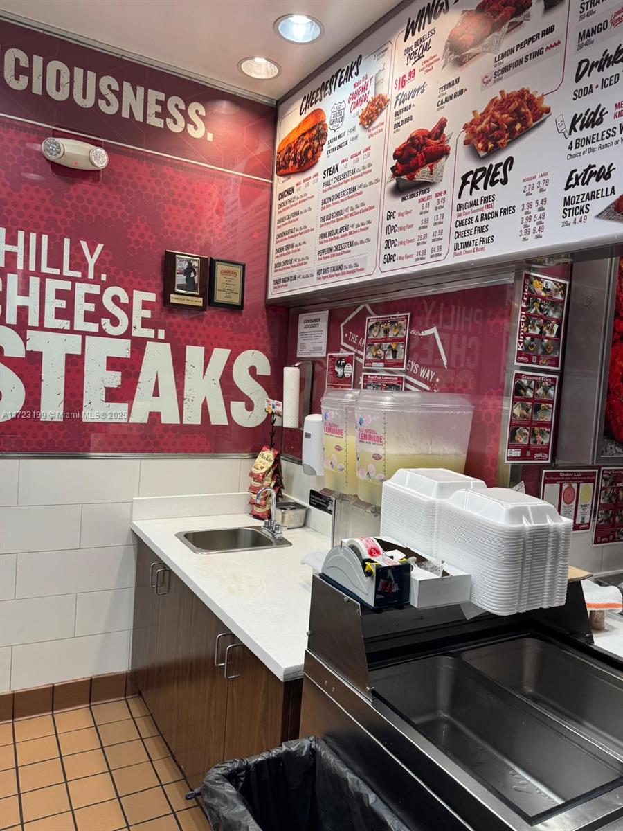 A commercial kitchen area features a menu board, a sink, and a stack of containers — 8000 W BROWARD BLVD, Plantation FL 33388, PLANTATION, FL
