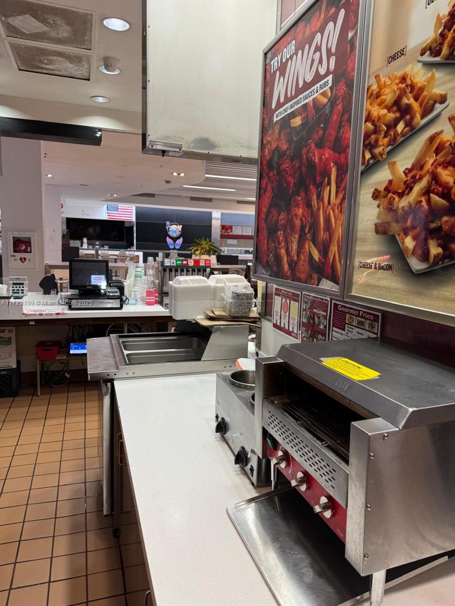 A commercial kitchen features stainless steel food preparation equipment and menu signage on the wall — 8000 W BROWARD BLVD, Plantation FL 33388, PLANTATION, FL