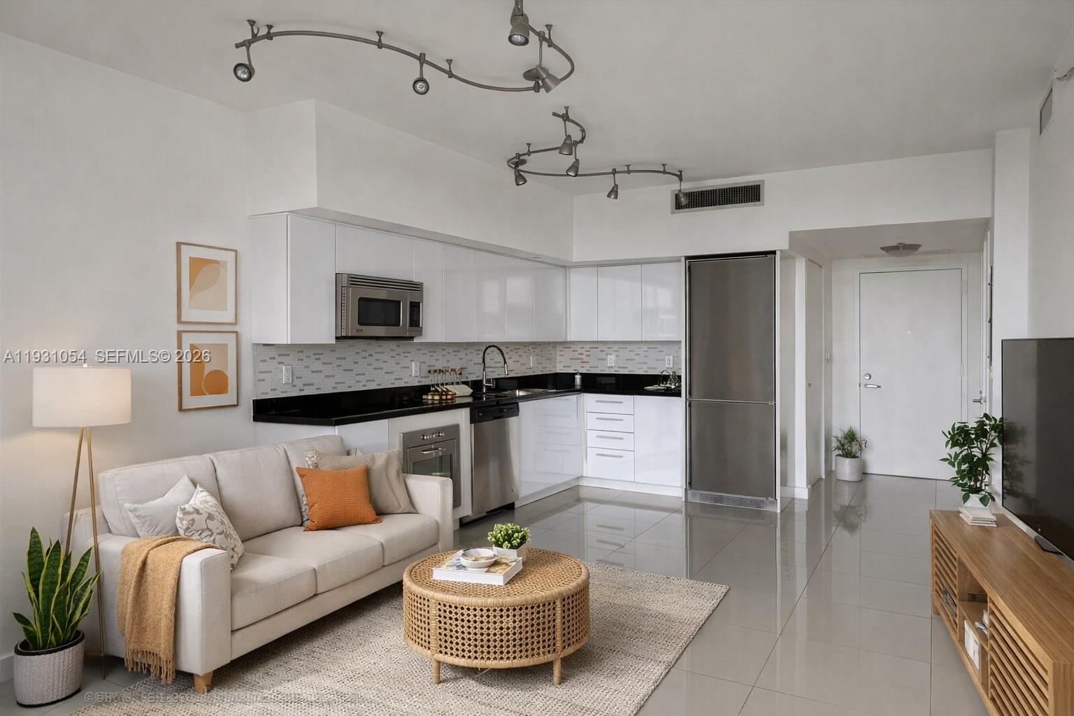 A modern living room and kitchen area features white cabinets, stainless appliances, and tile flooring — 92 SW 3rd St # 1408, Miami FL 33130, MIAMI, FL