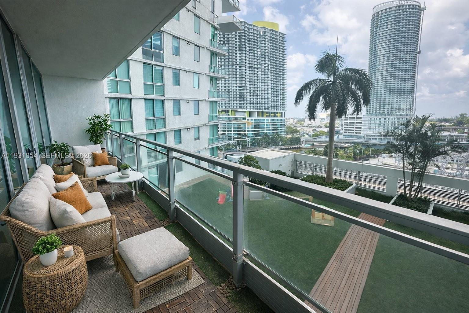 A balcony with outdoor furniture overlooks a green terrace and high-rise buildings — 92 SW 3rd St # 1408, Miami FL 33130, MIAMI, FL