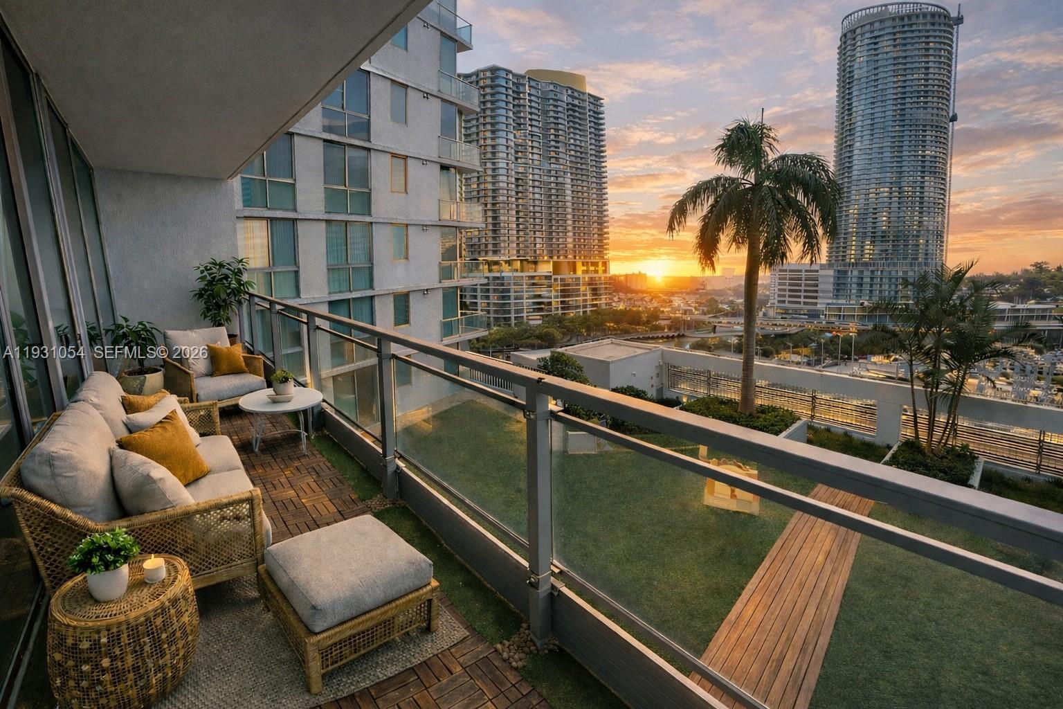A balcony with wicker furniture overlooks a grassy terrace and high-rise buildings at sunset — 92 SW 3rd St # 1408, Miami FL 33130, MIAMI, FL