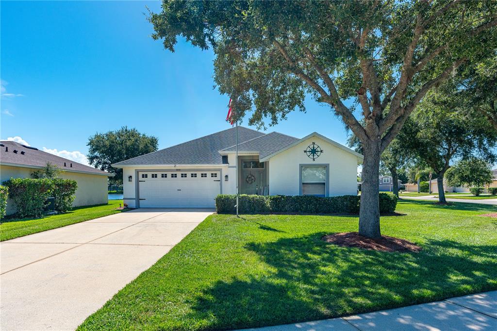 A single-story house with a white exterior, a two-car garage, and a large front tree — 6816 AMICI COURT, PORT ORANGE, FL