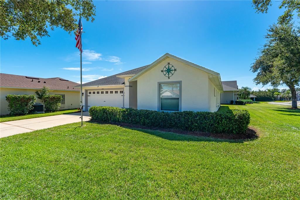 A single-story house with a white exterior, a two-car garage, and a compass rose decoration — 6816 AMICI COURT, PORT ORANGE, FL