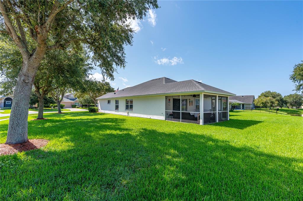 The exterior of a single-story house features a screened-in porch and a large grassy yard — 6816 AMICI COURT, PORT ORANGE, FL