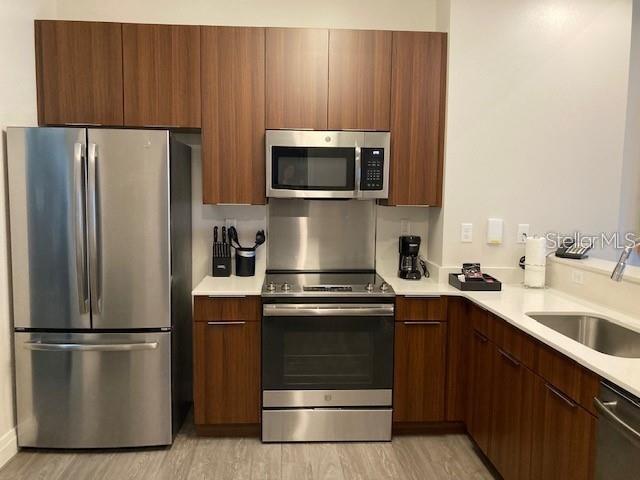 A kitchen features stainless steel appliances, wood-toned cabinetry, and white countertops — 14501 GROVE RESORT AVENUE UNIT 2119, WINTER GARDEN, FL