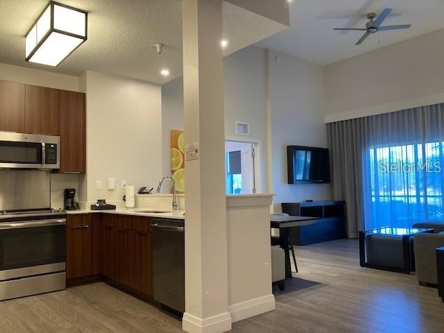 A modern kitchen with dark wood cabinets opens into a living area with large windows — 14501 GROVE RESORT AVENUE UNIT 2119, WINTER GARDEN, FL