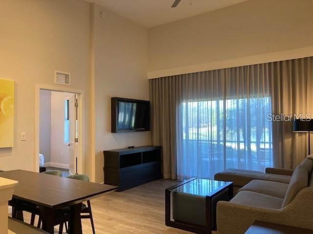 A living room with a dining table, television, and large windows with floor-to-ceiling curtains — 14501 GROVE RESORT AVENUE UNIT 2119, WINTER GARDEN, FL