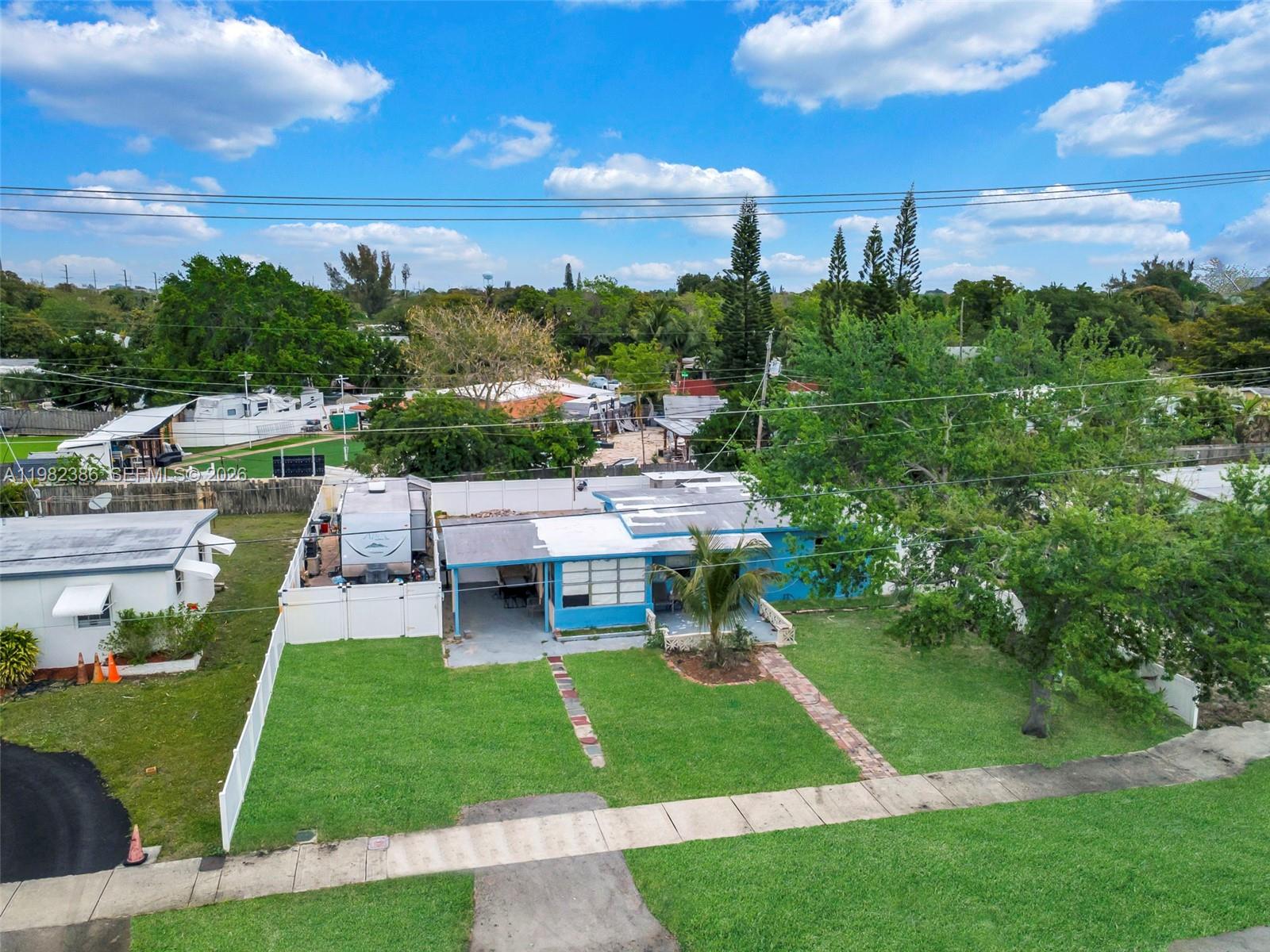 An aerial view shows a blue house with a white fence and a large tree — 1449 NE 51st St, Pompano Beach FL 33064, POMPANO BEACH, FL