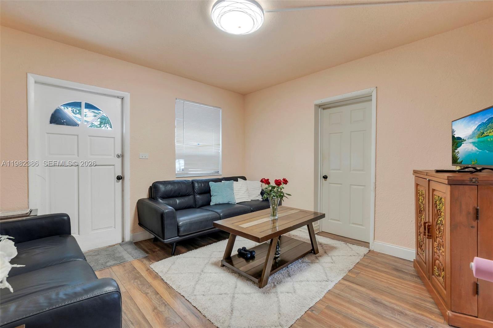 A living room features two black leather sofas, a wooden coffee table, and a television — 1449 NE 51st St, Pompano Beach FL 33064, POMPANO BEACH, FL