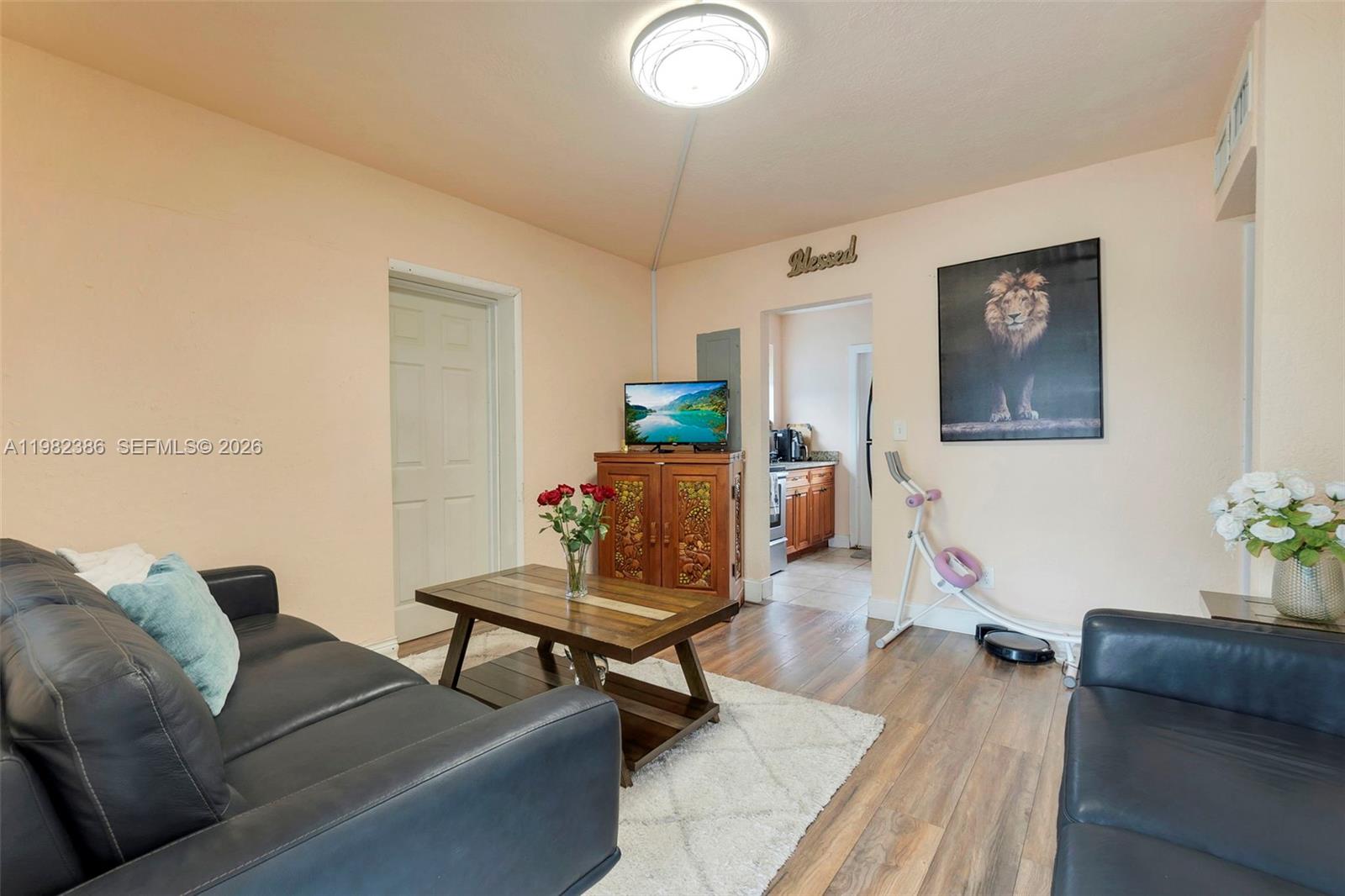 A living room features dark leather sofas, a wooden coffee table, and a lion portrait — 1449 NE 51st St, Pompano Beach FL 33064, POMPANO BEACH, FL