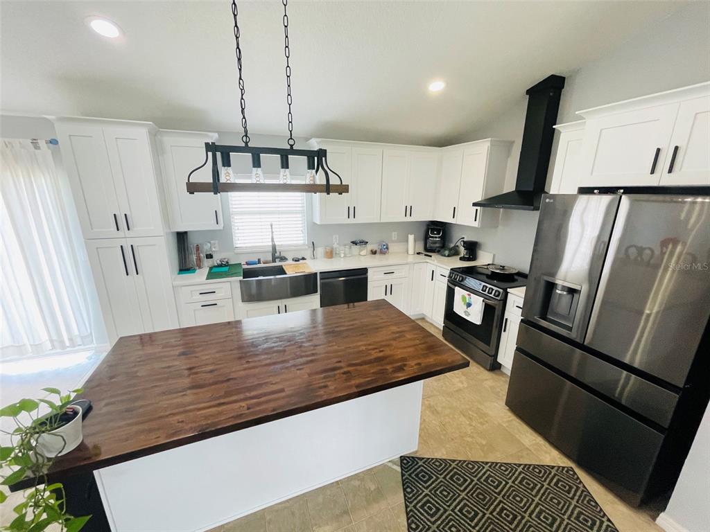 A kitchen features white cabinets, a dark wood island countertop, and stainless steel appliances — 346 PUFFER COURT, POINCIANA, FL