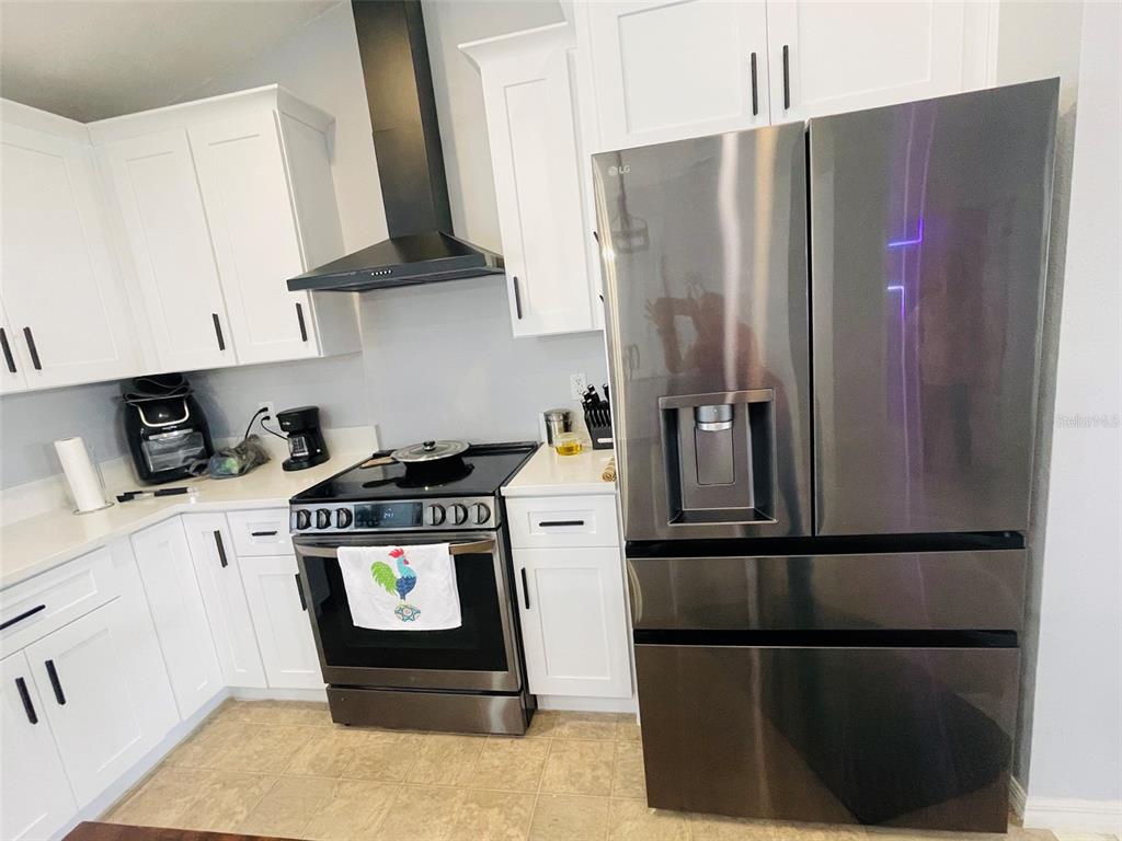 A kitchen features white cabinets, stainless steel appliances, and a black range hood — 346 PUFFER COURT, POINCIANA, FL