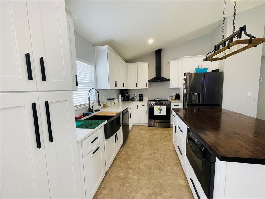 A kitchen features white cabinets, a dark wood island countertop, and stainless steel appliances — 346 PUFFER COURT, POINCIANA, FL
